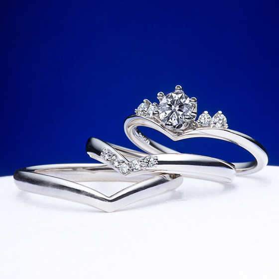 ティアラ型をイメージした婚約指輪に重なるV字の結婚指輪。ダイヤモンドの留め方を変えることで、婚約指輪はより華やかな印象に仕上がります。