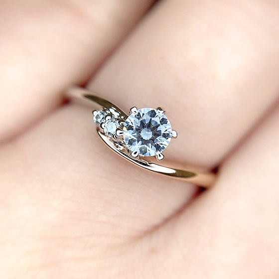 ダイヤモンドを抱え込むようにデザインされた優しい雰囲気の婚約指輪。