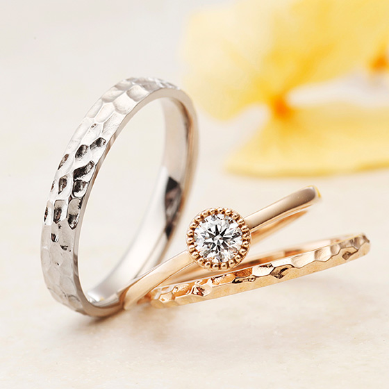 表面に凹凸をつけた槌目模様の結婚指輪とのセットリングで上品な印象に。