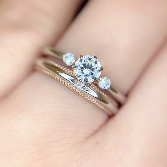 ストレートラインがピッタリと合った婚約指輪と結婚指輪のセットリング。結婚指輪のミル打ち加工がおしゃれ。