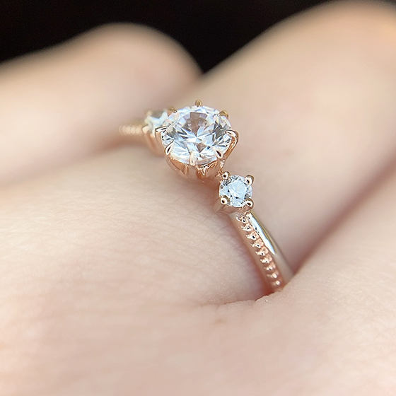 ダイヤモンドを支えるシャトン部分とミル打ちデザイン部分がゴールドで作られたコンビネーションデザインの婚約指輪。