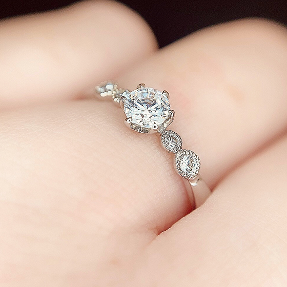 メレダイヤモンドを囲うミル打ち加工がアンティークな婚約指輪。