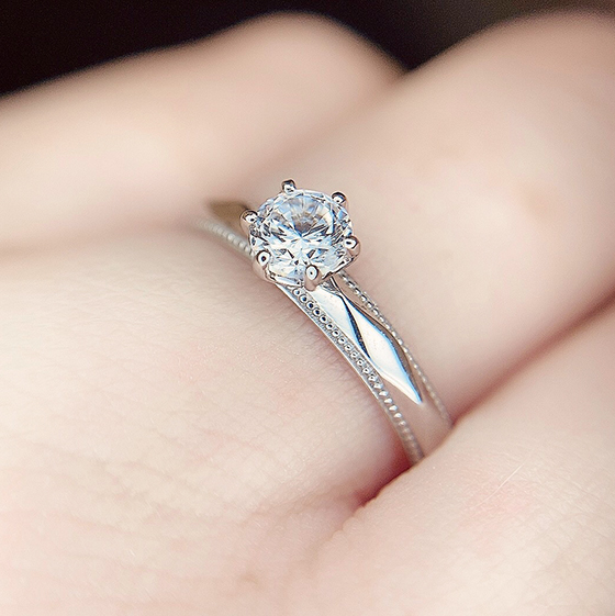 ソリティアタイプ(一粒石)には珍しい、ダイヤモンドに加えカット面の輝きも堪能できる華やかなデザインの婚約指輪。