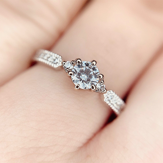 中央に絞られたデザインが可愛らしい婚約指輪。サイドにセットされたメレダイヤモンドが存在感を放ちます。