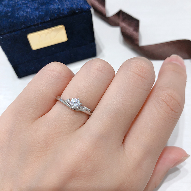 V字ラインが指を細く長く演出。流れ星のようなメレダイヤモンドの輝きが特徴的な婚約指輪（エンゲージリング）。