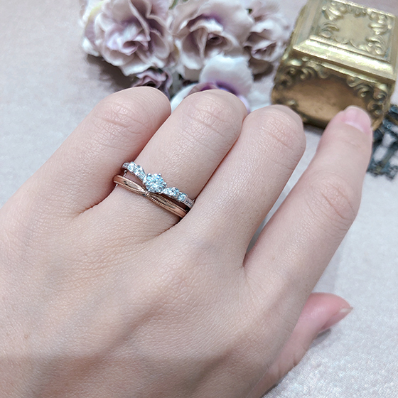 リボンデザインを違った形で表現した婚約指輪と結婚指輪のセットリング。それぞれのリボンデザインが可愛らしく女性を虜にさせます。
