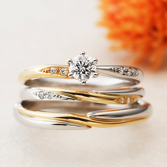 ゴールドとプラチナの2色使いの結婚指輪とのセットリング。クロスに仕上げたマリッジリングはシャープで大人な印象に。