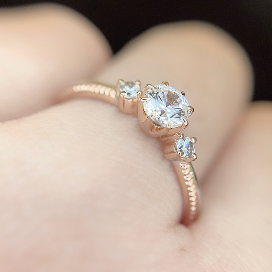 ダイヤモンドを支えるシャトン部分とミル打ちデザイン部分がゴールドで作られたコンビネーションデザインの婚約指輪。