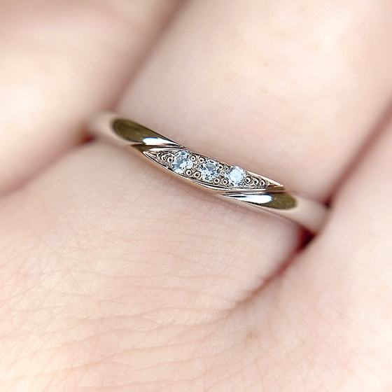 柔らかなカーブを描く結婚指輪。ダイヤモンドをセットした部分のパーツをゴールドでつくられておりダイヤモンドとゴールドの色味がおしゃれ。