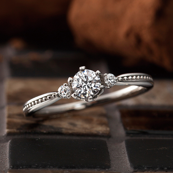 両サイドにダイヤモンドを留め、ミル打ちでアレンジした婚約指輪。モダンで華やかな印象に。