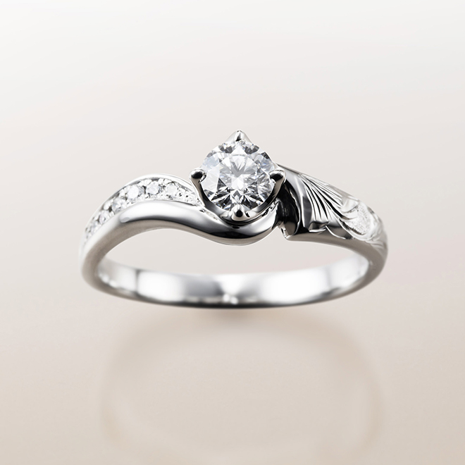 片側にはスクロール、もう片側にはお二人を祝福する花々をメレダイヤモンドで表現した婚約指輪（エンゲージリング）
