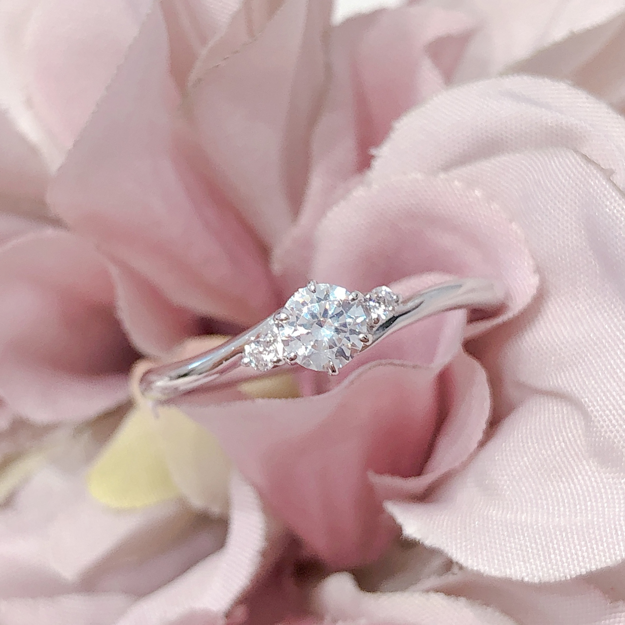 中央のダイヤモンドに花を添えるようにセットされたサイドのメレダイヤモンドが可憐な印象を与えてくれる婚約指輪です。