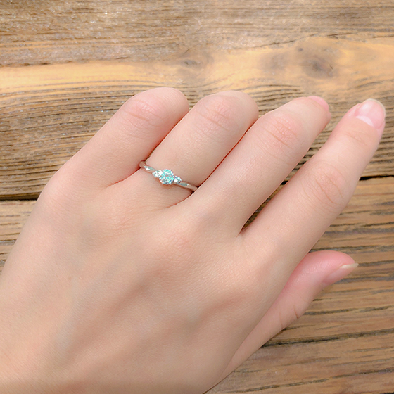 中心のダイヤモンドの両脇にメレダイヤが寄り添う可憐な印象の婚約指輪です。カットが施されているのでリング自体が光を受けて輝きます。