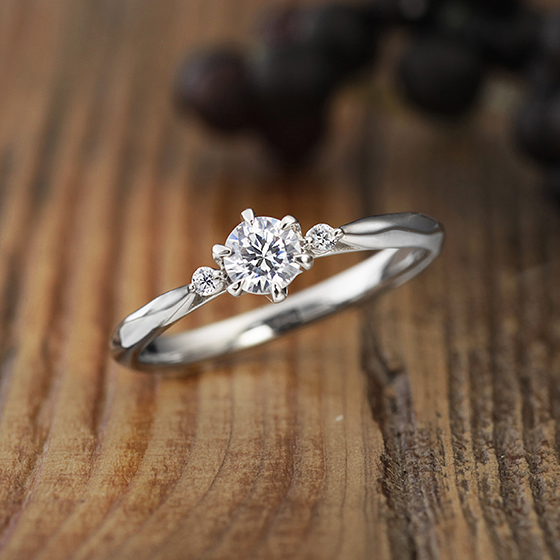 シンプルで人気デザインの婚約指輪（エンゲージリング）センターダイヤモンドの両サイドにメレ（小粒）ダイヤモンドが2石デザインされています。