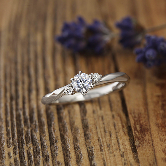 緩やかなウェーブラインの婚約指輪（エンゲージリング）両サイドのメレダイヤモンドが華やかさを演出してくれます。