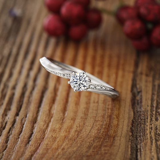 緩やかなSラインの婚約指輪（エンゲージリング）両サイドに流れるようにメレダイヤモンドが入っていて人気デザイン。