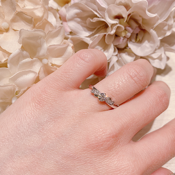 女性に人気、リボンモチーフの婚約指輪（エンゲージリング）です。メレダイヤをピンクサファイヤへ変更することもOK