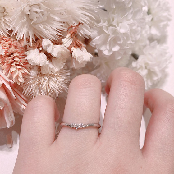 中央に3石のダイヤモンドがV字に留められたキュートなデザインの結婚指輪です。爪留めのダイヤモンドは光を取り込んで埋め込みタイプよりも輝きを楽しめますね。