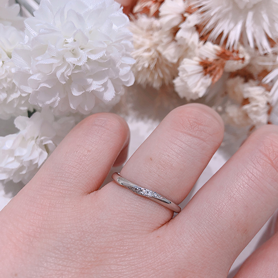 ひねりの効いたデザインにダイヤモンドが留められた女性らしいデザインの結婚指輪です。