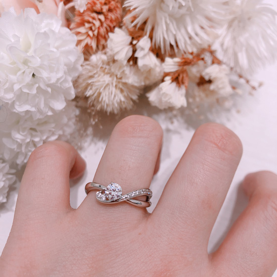 滑らかなウエーブラインがフェミニンな印象の婚約指輪。アシンメトリーデザイン、左側に2石、右側の腕には7石メレダイヤモンド留められたゴージャスな婚約指輪（エンゲージリング）です。