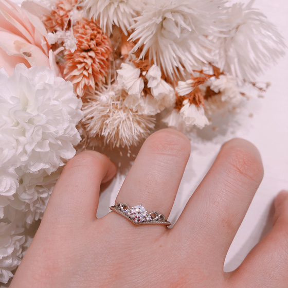 V字ラインが指を華奢に、細長く見せてくれるデザインです。透かし模様から肌色が見え女性らしい印象の婚約指輪に。
