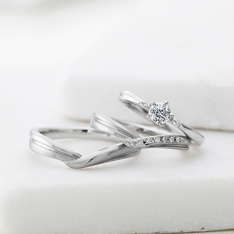 お二人がぎゅっと手を握り合っているようなデザイン。程よいダイヤが派手になりすぎず、着けやすい作りです。