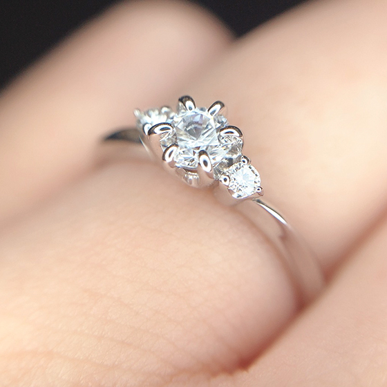 センター中央のダイヤモンドとそれに寄り添うメレダイヤモンドが可愛らしい婚約指輪のデザインです。