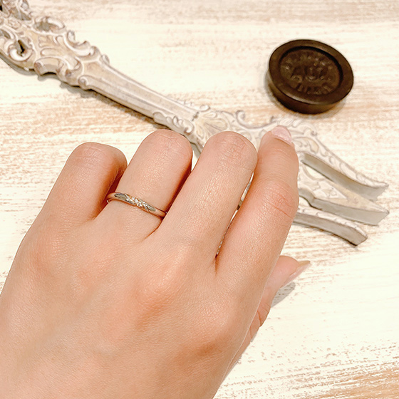３石あしらったダイヤモンドのサイドにミル打ちが施されたアンティーク感漂うデザインの結婚指輪です。