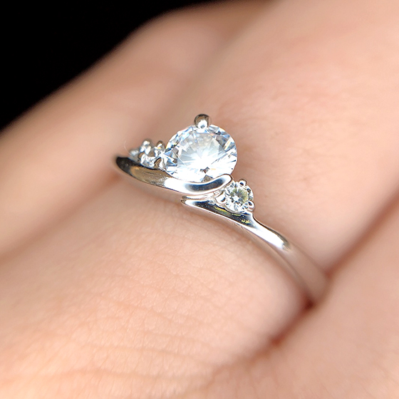ダイヤモンドを抱え込む様にデザインされた婚約指輪。軽やかなデザインが心躍ります。
