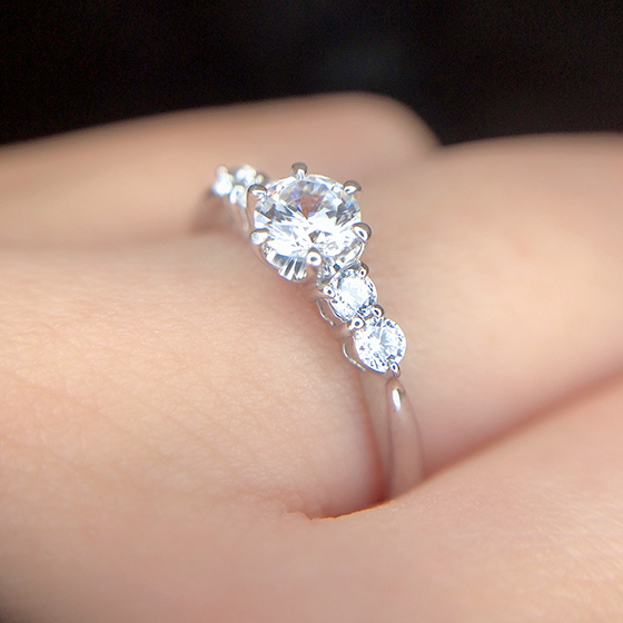 中央に輝きを集めた婚約指輪。メインのダイヤモンドとサイド2Pづつセットされたメレダイヤモンドが華やか。