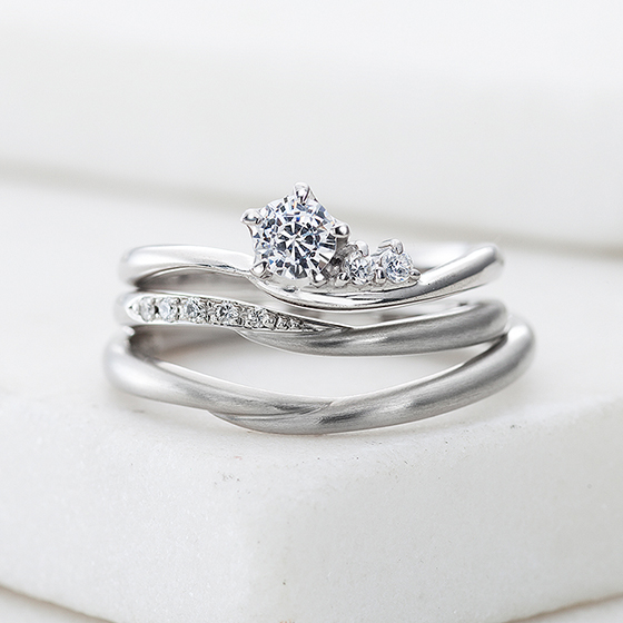 中心ダイヤに沿うようにメレダイヤモンドが置かれ、可愛らしいデザインの婚約指輪。