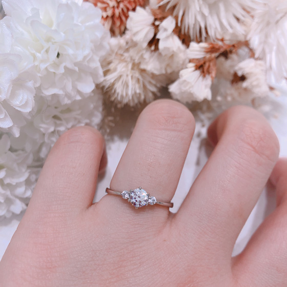 両サイドのメレダイヤモンドが主役のダイヤモンドをより大きく魅せてくれるデザインです。細身でストレートタイプの婚約指輪は、結婚指輪との重ね付けもしやすい。