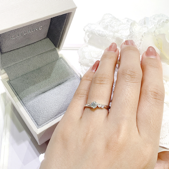 片側のみにセットされたメレダイヤモンドがキュートな印象を与えてくれる婚約指輪です。