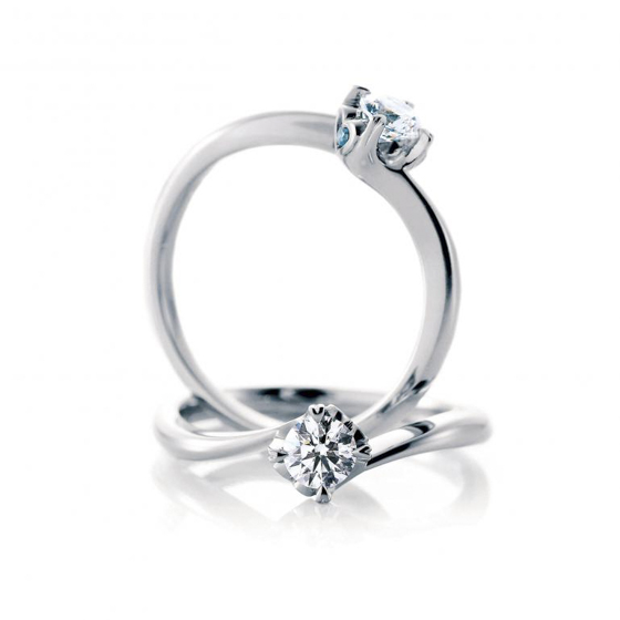 ダイヤモンドを上下からプラチナのアームで包んだシンプルなソリティアタイプの婚約指輪。側面のハートモチーフからはブルーダイヤモンドが。