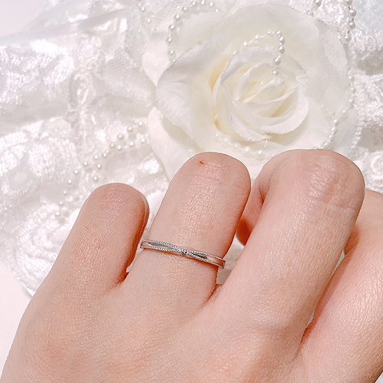 中心に向かってシェイプされたデザインがリボンのようで可愛らしい結婚指輪。