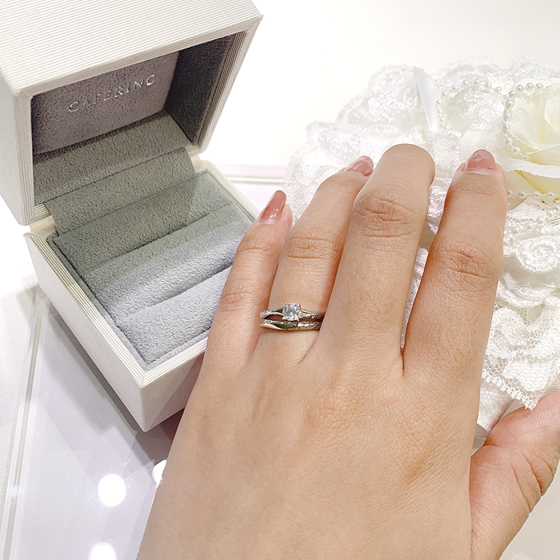 婚約指輪とのセットリング。結婚指輪の中央のヘコミ部分に婚約指輪のダイヤモンドがキレイに収まるようデザインされています。サイドにセットされたダイヤモンドもリンクしてより華やかな印象になります。